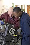 Teacher helping student with car engine