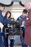 Teacher helping students with car engine