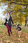 Smiling woman walking dog in park