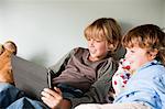 Two young boys on a bed, using a digital tablet