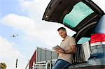 Man using data tablet in airport carpark