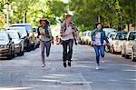 Three friends running through city street