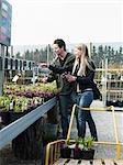 Young couple standing in garden market, smiling