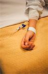 Girl lying on hospital bed with IV drip on arm