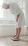 Older woman weighing herself in bathroom