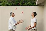 Father teaching son to juggle outdoors