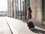 Businesswoman rolling luggage outdoors