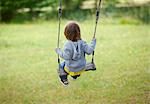 Children sitting in swing in backyard