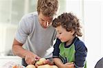 Father helping son peel potatoes