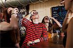 Young friends drinking from shot glass in bar