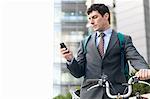 Mid adult businessman with bike using cellphone