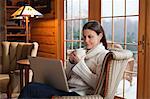 Mature woman relaxing in armchair with laptop