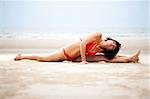 Beautiful woman doing yoga and stretches exercise on the beach