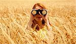 Redhead girl with binocular at wheat field.