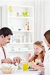 A happy family with a child eating breakfast in the kitchen