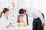 The father kisses his daughter before leaving the kitchen