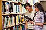 Young adults reading a book in a library