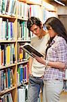 Portrait of young students looking at a book in a library