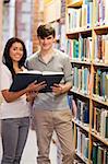 Portrait of smiling students holding a book in a library