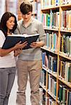 Portrait of happy students reading a book in a library