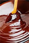 Wooden spoon stirring soft melted rich chocolate