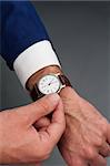 male worker adjusts an old wristwatch on grey background