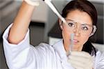 Brunette woman pouring a liquid in a tube in a laboratory