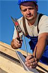 Carpenter working on the roof driving a nail in - shallow depth