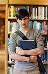 Portrait of young student holding a book in the library