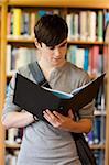 Portrait of a smiling student looking at a binder in the library