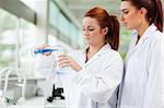 Cute scientists pouring liquid in an Erlenmeyer flask in a laboratory