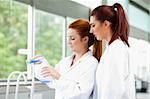 Young scientists pouring blue liquid in an Erlenmeyer flask in a laboratory