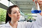 Brunette looking at a blue liquide in a laboratory