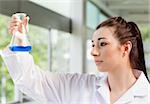 Cute science student looking at a blue liquid in an Erlenmeyer flask