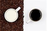 A cup of black coffee on white background and a cup of white milk on a layer of coffee beans