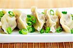 Plate of cooked chinese dumplings in a row