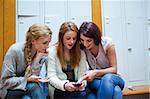 Student showing a text message to her friends in a cloakroom