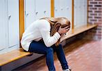 Depressed student sitting on a bench in a corridor
