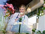 Young attractive woman working in flower shop, preparing bouquet and smelling white roses