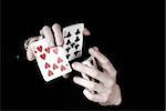 Young magicians hands holding a lot of play cards. black background