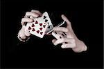 Young magicians hands holding a lot of play cards. black background