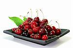 fresh red cherries and leaves in a bowl on white background