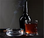 Color photo of a glass of whiskey and cigarettes