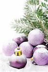 Fir and purple christmas baubles with snow.