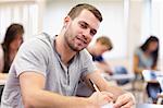 Smiling young adult writing in a classroom