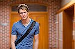 Handsome student standing up in a corridor