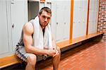 Handsome young sports student sitting on a bench with a towel