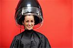 Woman under a hairdressing machine against a red background