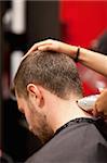 Portrait of a male young student having a haircut with a hair clippers