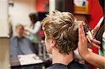 Blond-haired man having a haircut with scissors